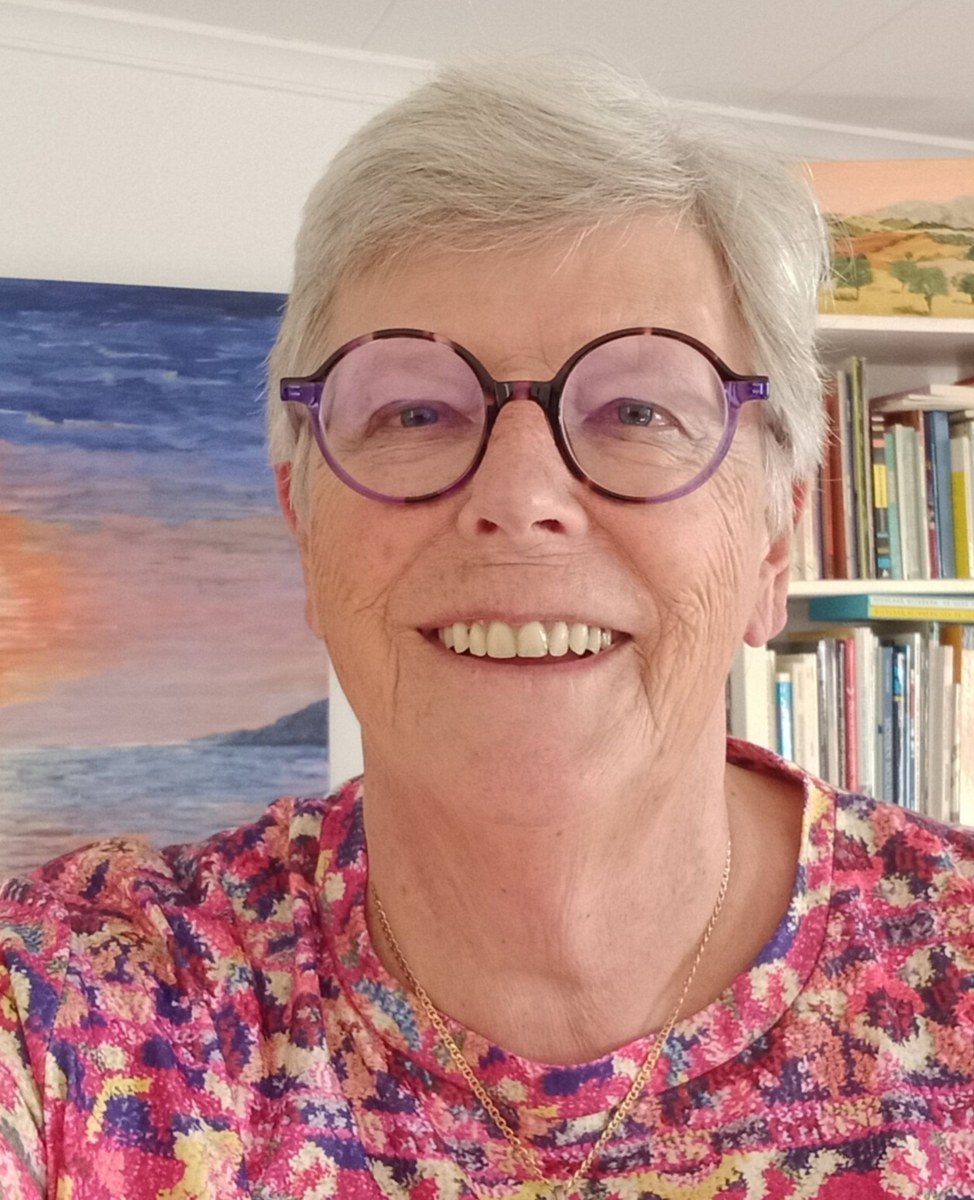 Mercedes Choufoer smiling beside her artwork and books